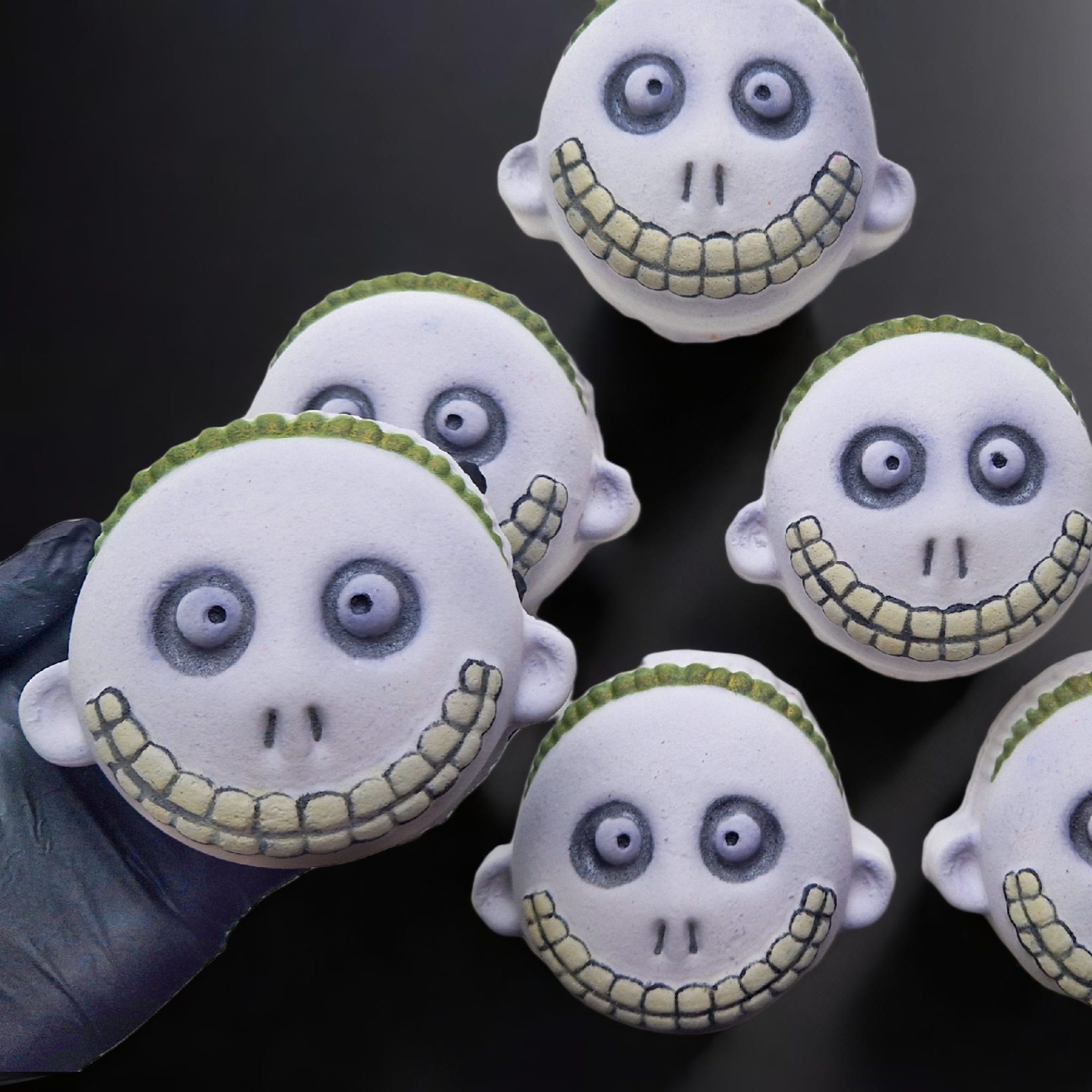 Bath bombs designed to resemble a character with a tricks or treaters face, predominantly gray with green and white accents.