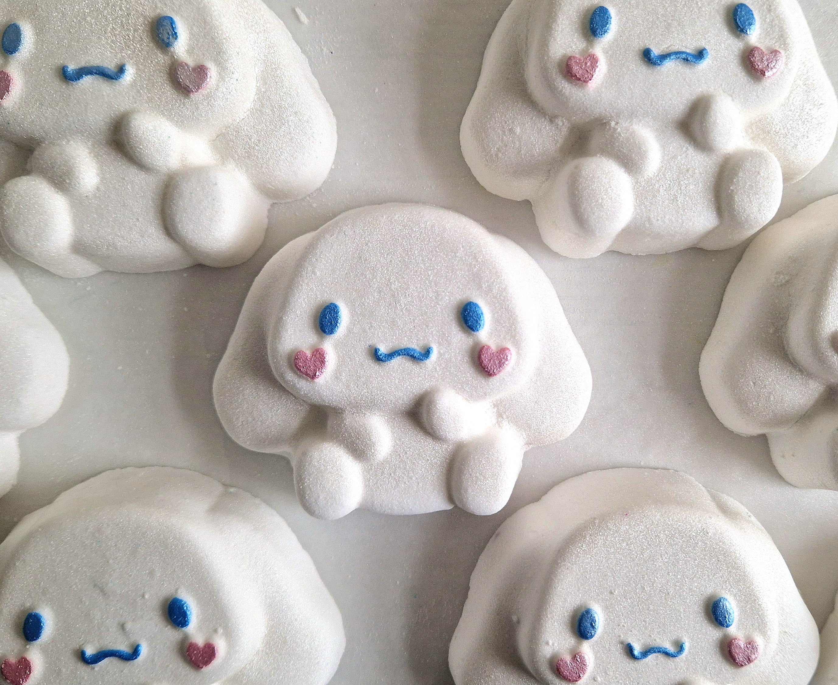 A kawaii cinnamoroll shaped bath bomb from Fizz Bomb Cosmetics, on a black background. Featuring pin and blue detailing – a fun, kawaii themed bath treat perfect for gifting or relaxing self-care days.