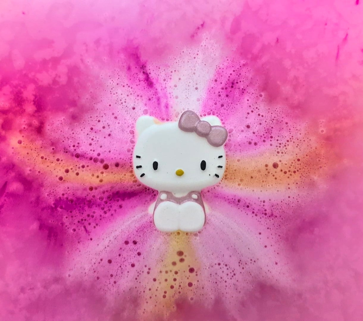 A Kawaii Hello Kittybath bomb in the bath from Fizz Bomb Cosmetics, featuring pink and yellow colours bursting – a fun, Hello Kitty themed bath treat perfect for gifting or relaxing self care days.