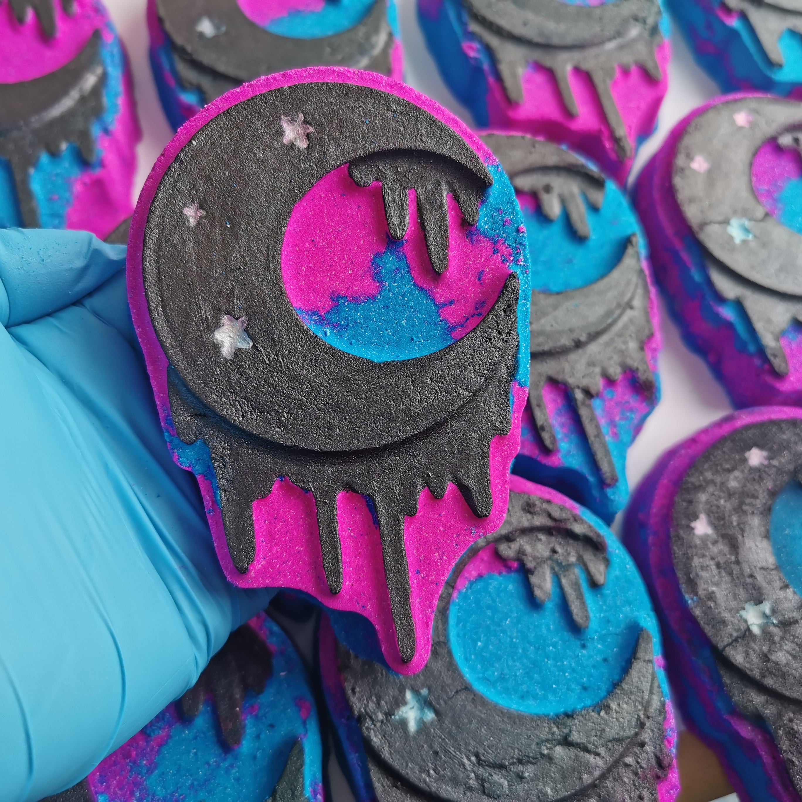 Handmade bath bombs with black, pink, and blue colors, featuring a moon and stars design.