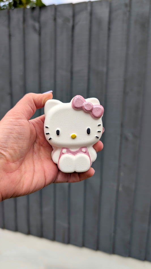 Hand holding a Kawaii Hello Kittybath bomb from Fizz Bomb Cosmetics, featuring pink and yellow detailing – a fun, Hello Kitty themed bath treat perfect for gifting or relaxing self care days.