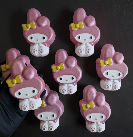 A kawaii my melody shaped bath bomb from Fizz Bomb Cosmetics, on a black background. Featuring pink and yellow detailing – a fun, kawaii themed bath treat perfect for gifting or relaxing self-care days.